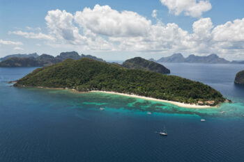 Aerial view of Pangulasian Island Resort in El Nido, Palawan, surrounded by turquoise waters, lush greenery, and a pristine white-sand beach.